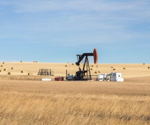 A single oil pump jack in the farm field. Oil industry equipment. Calgary, Alberta, Canada.
